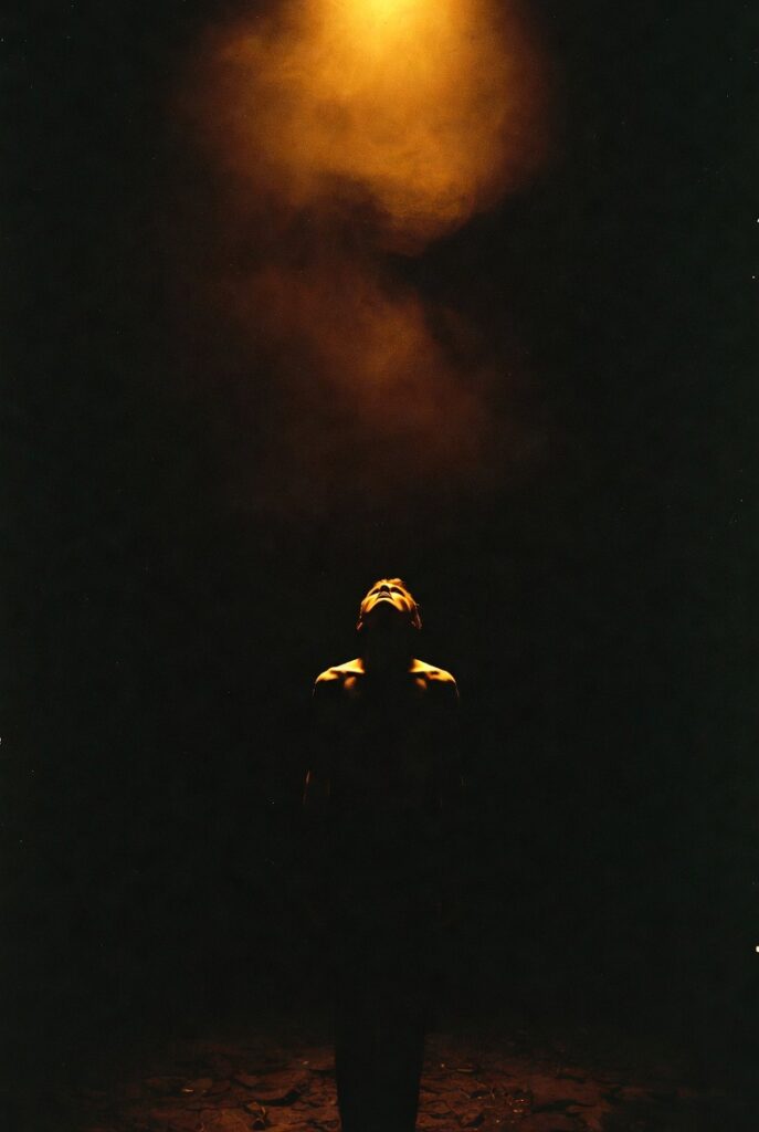 Figura humana solitária contemplando uma luz dourada distante na escuridão, imagem de encerramento do artigo sobre a EQM negada