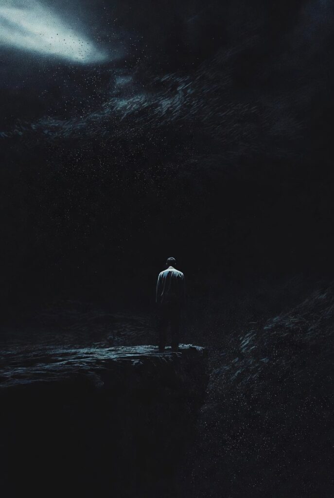 alt="Silhueta de uma pessoa de costas, parada na beira de um abismo negro infinito, representando o vazio eterno e o terror existencial das Experiências de Quase-Morte negativas (EQMs distressantes)"